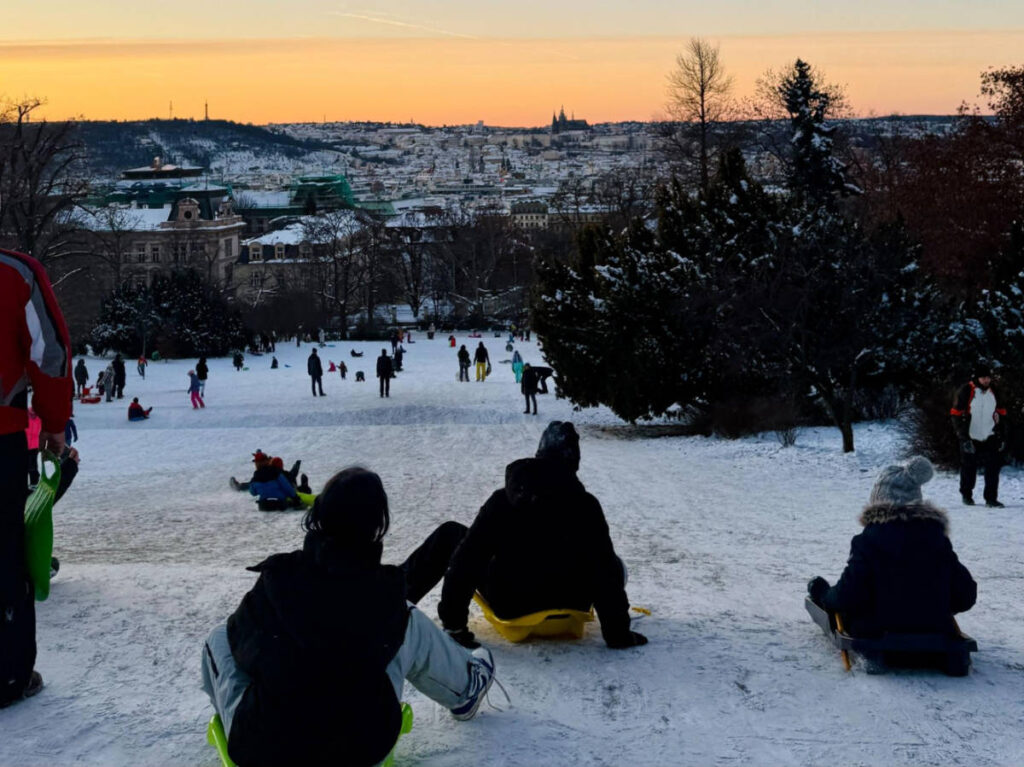 People enjoying at the sledding spot in Reigrovy Sady at sunset