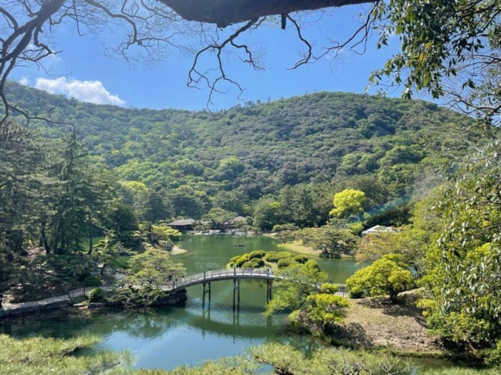 Scenic view of a small bridge in the middle of Ritsurin Garden surrounded by greenery