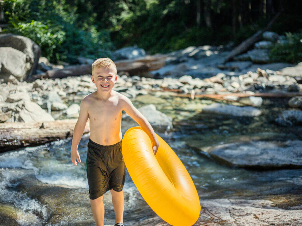 A kid holding an inflatable tube for the river tubing in Davidson River