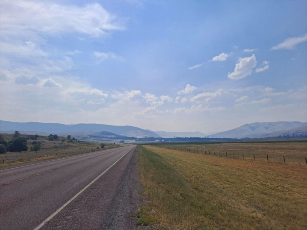 A long empty road with mountains in the background and a bit of haze