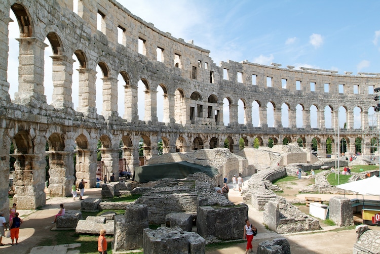 Tourists walking on the ruins of Roman amphitheater at Pula