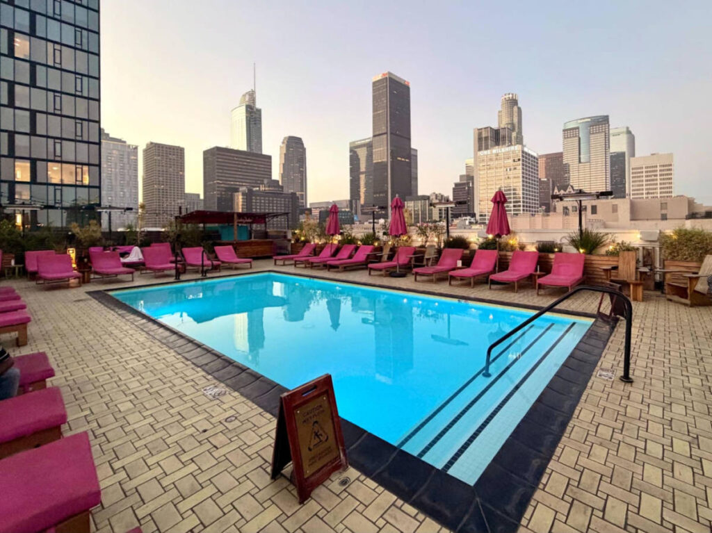 View of the pink lounge chairs around the blue rooftop pool at the Freehand hotel