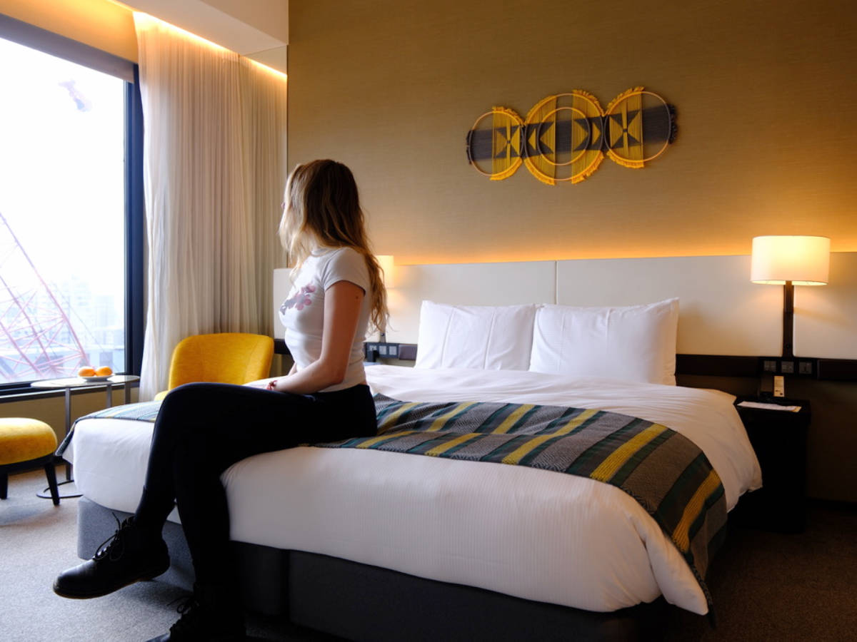 The author, Sky Ariella sitting on her bed while admiring the view at her room in MGH Mitsui Garden Hotel