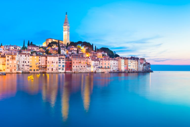 The cityscape of Rovinj reflecting on the water at night