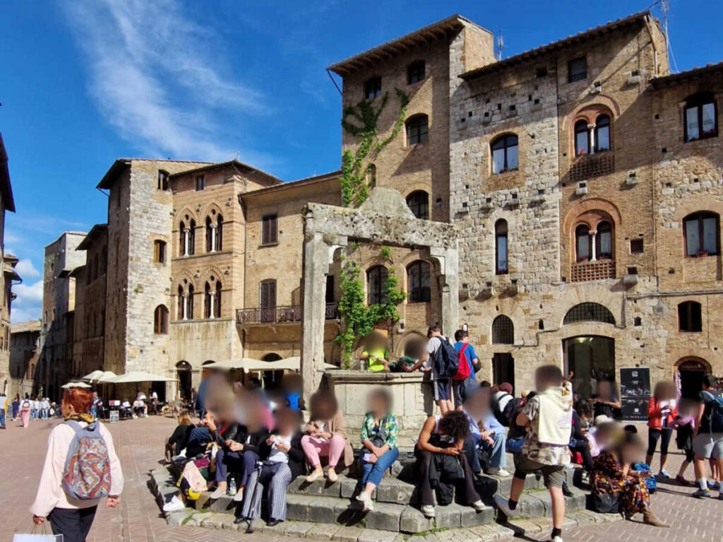 People sitting around San Gimignano Piazza della Cisterna