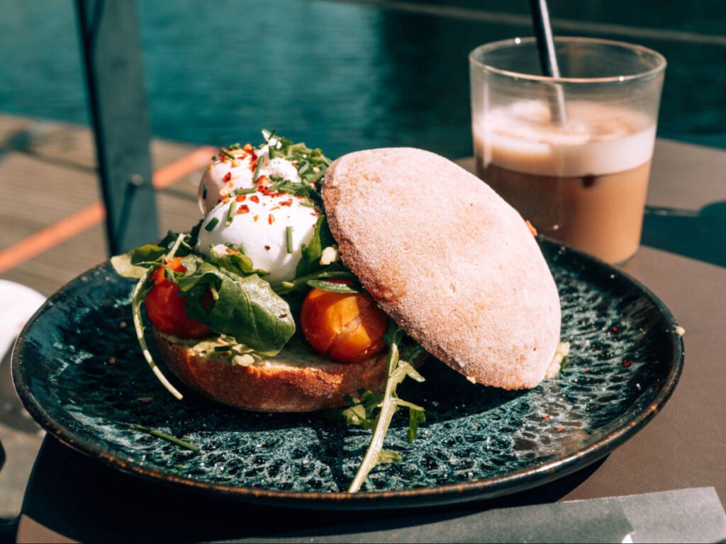 A plate with breakfast sandwich and cup of coffee