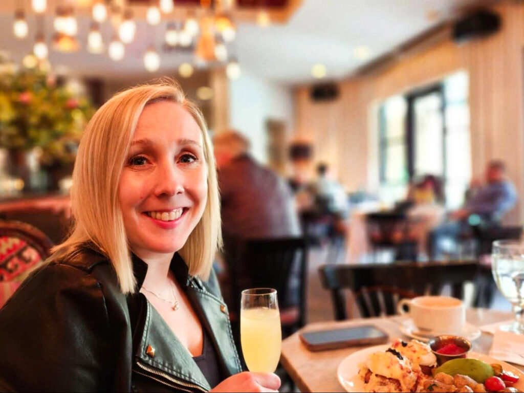 The author Sarah Heath, posing for a photo while holding a glass of drink at the Dragonfly