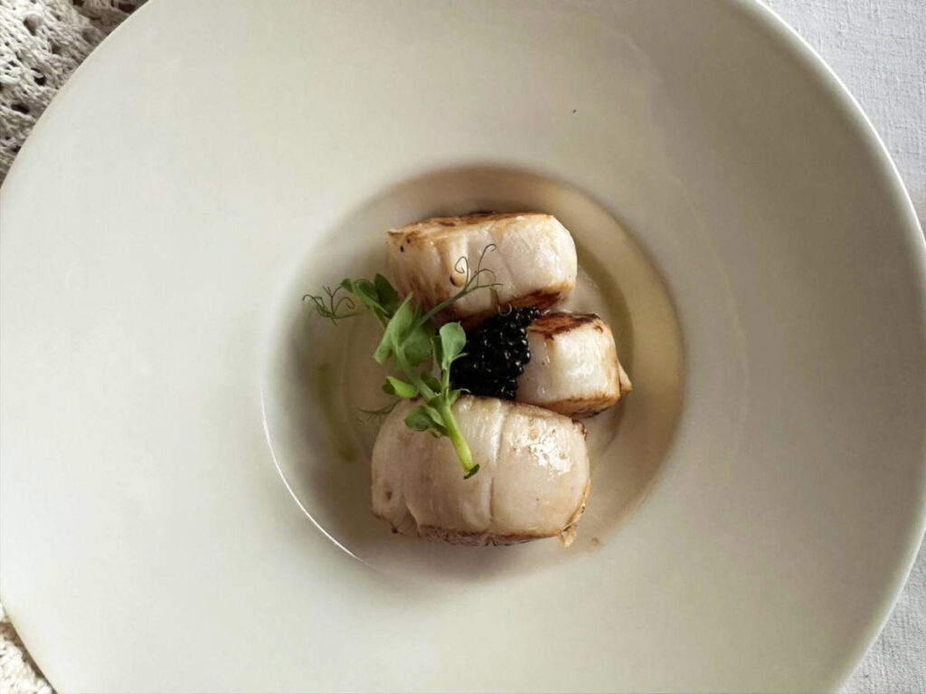 Three scallops topped with caviar and greens