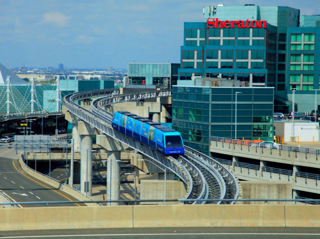 A blue train traveling on tracks near Toronto Pearson Airport