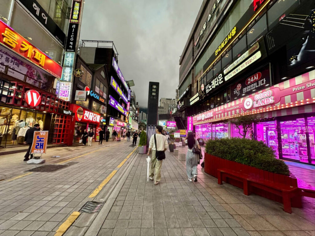 People walking along the shopping street with colorful lights in Seomyeon at dusk