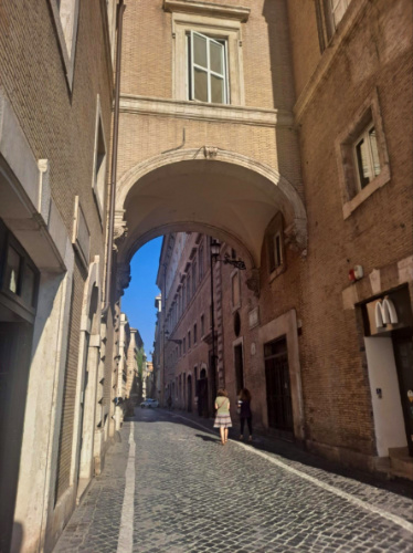 A narrow street in Rome featuring an archway, surrounded by historic buildings