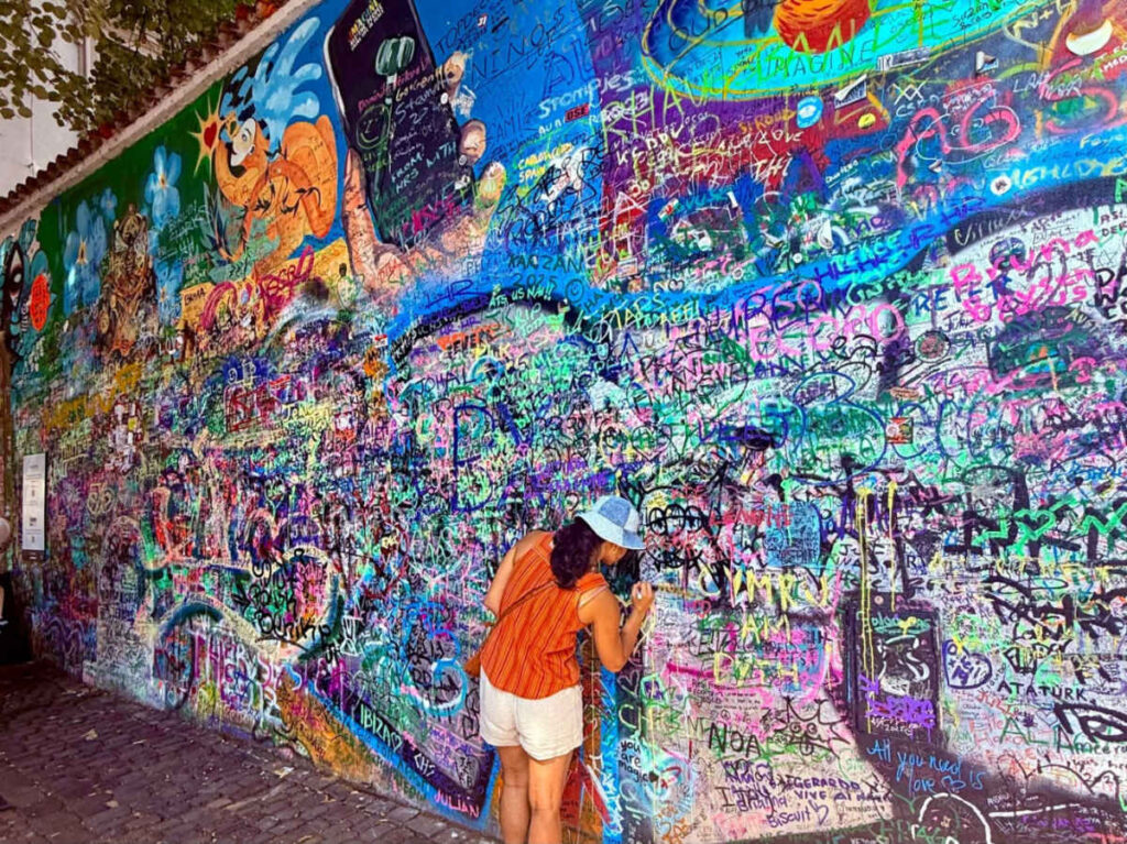 A woman signing at the Lennon Wall full of graffiti
