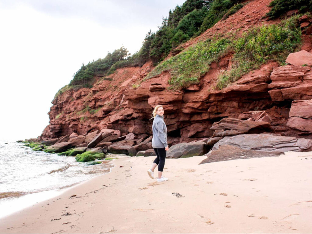 The author Taylor Herperger smiling for a photo at Singing Sands Beach
