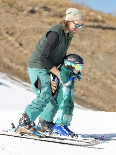 A ski instructor teaching a little boy how to ski