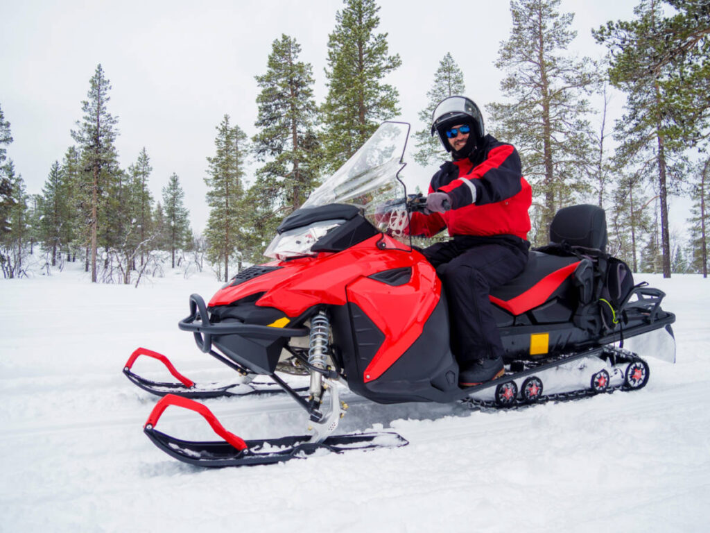 A smiling man riding a snowmobile