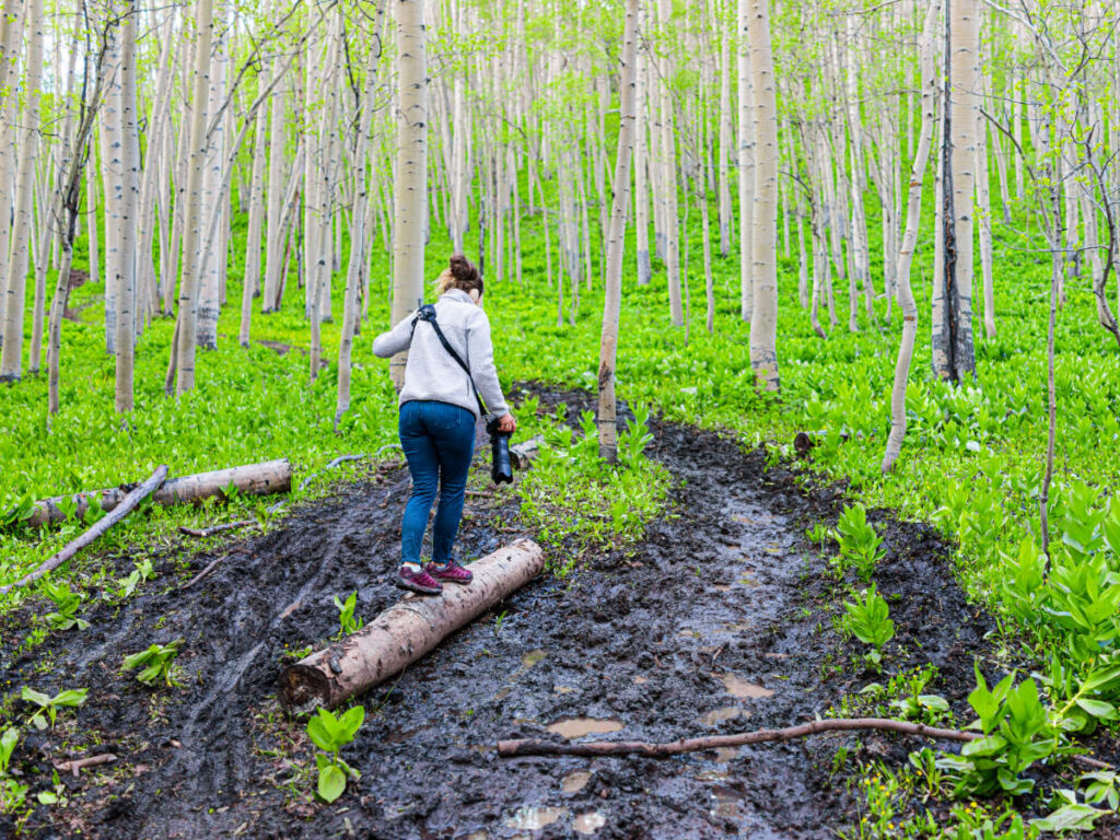 A woman crossing a muddy trail at Snodgrass Trail