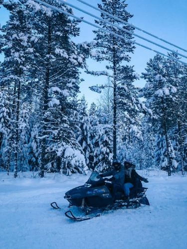 People riding a snowmobile along the woods near Tartu