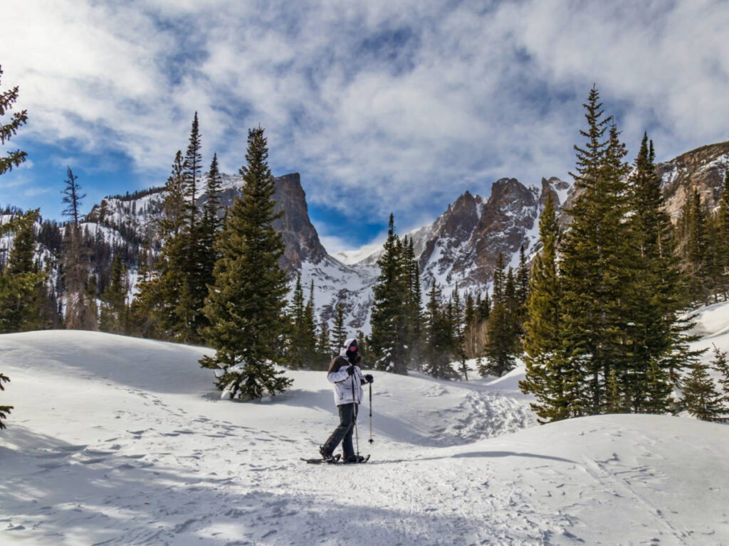 A man snowshoeing around the snow covered Rocky Mountain National Park
