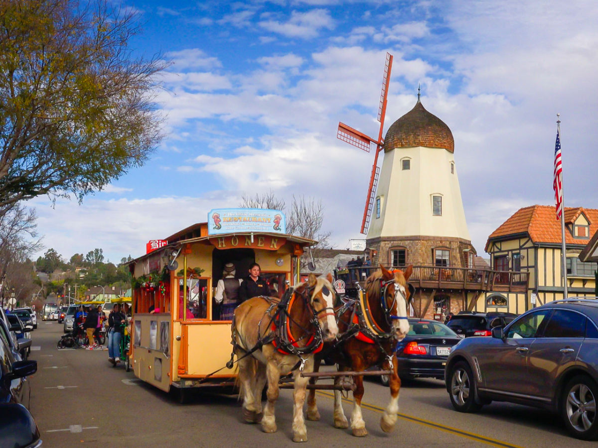 A horse drawn carriage and tourists enjoy the Danish inspired streets of Solvang, California