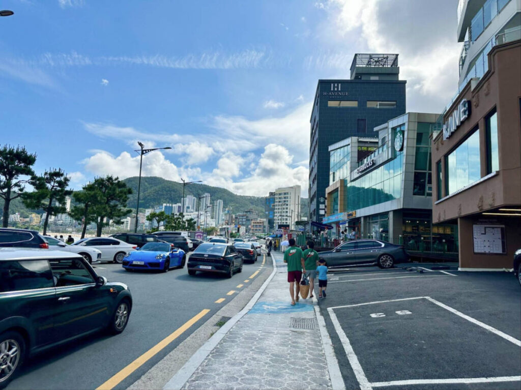 People walking along the beachfront street at Songjeong Beach