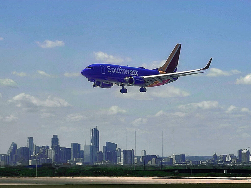 A Southwest Airlines plane lands in front of the Austin skyline