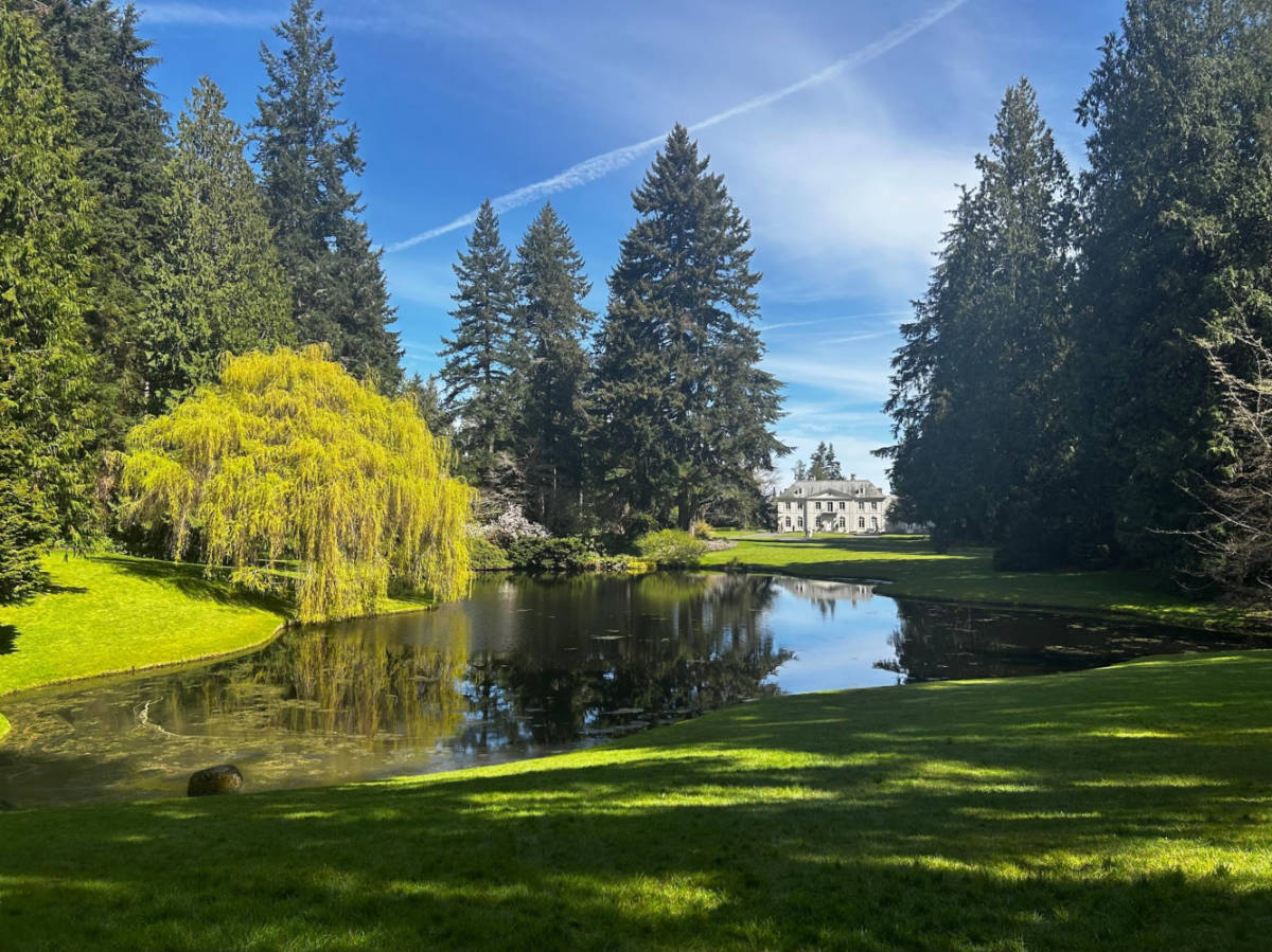 Picturesque view of the Bloedel Reserve featuring a reflecting pond and a French-inspired villa