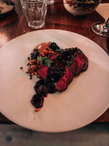 A plate with steak topped with sauce in Gitane