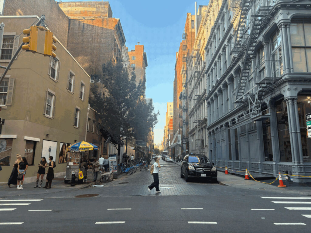 A lady walking on a cobblestone street in SoHo