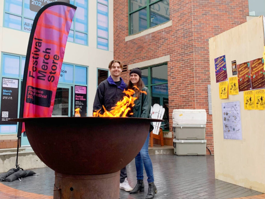The author Betty Hurd with her boyfriend smiling for a photo while keeping their self warm by the fire
