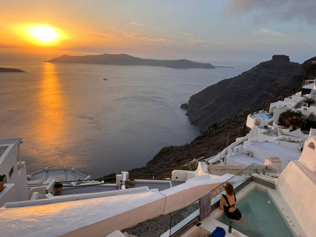 A woman enjoying the sunset views from the pool of the hotel in Santorini