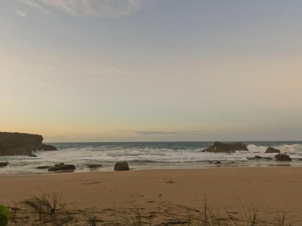 View of the waves crashing along the shoreline at Poza de Matos at sunset