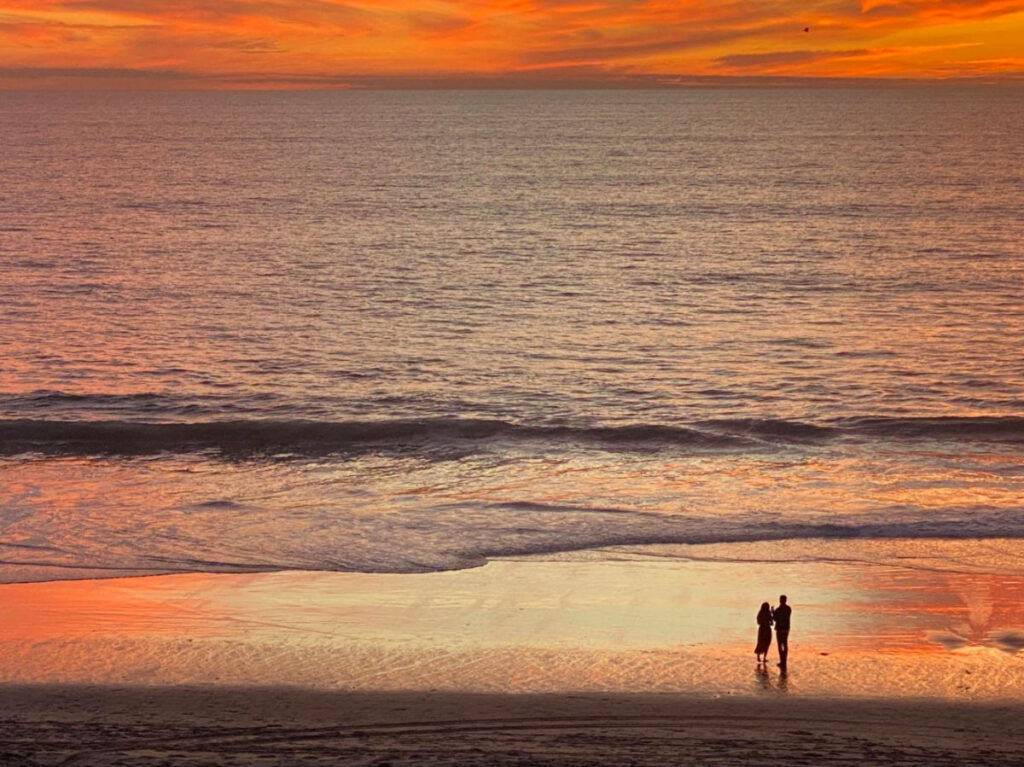 A couple enjoying the sunset on the beach in Carlsbad