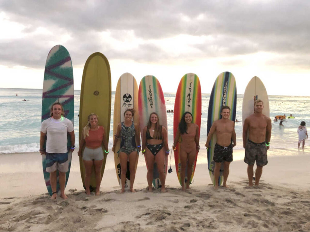 The surfers holding their surfboards along the shoreline
