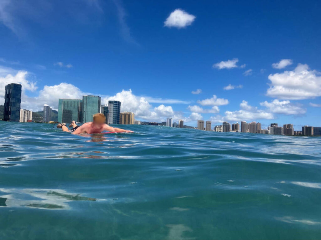 A man paddling to surf with skyline views in the background at Marinelands