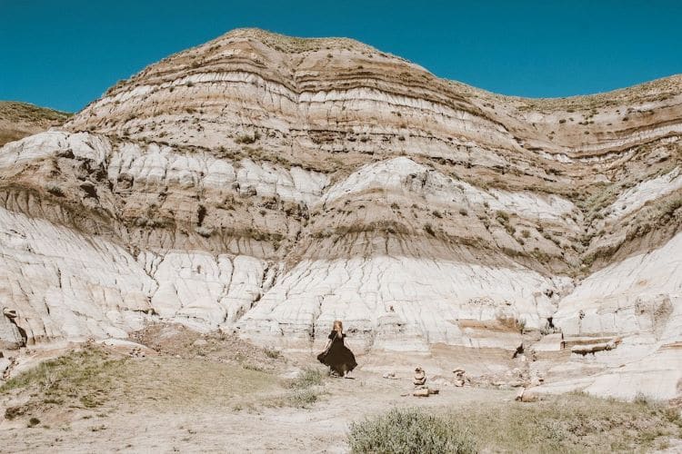 The author Taylor stands in front of layers of settled rock in Drumheller