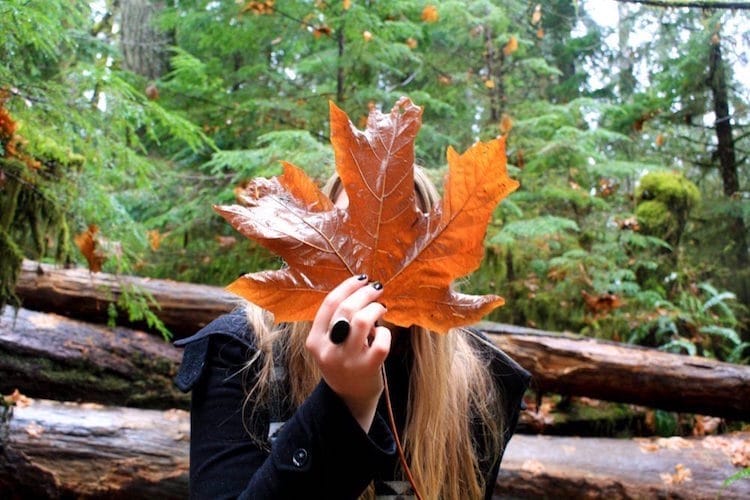 Taylor holding a large orange leaf in front of her face in Vancouver Island, British Columbia