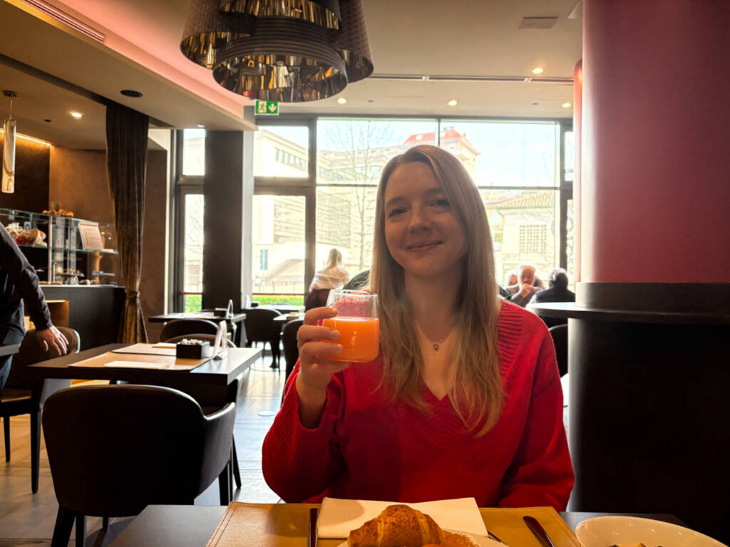 The author Taylor Herperger, holding a glass of drink at breakfast in Leonardo Royal