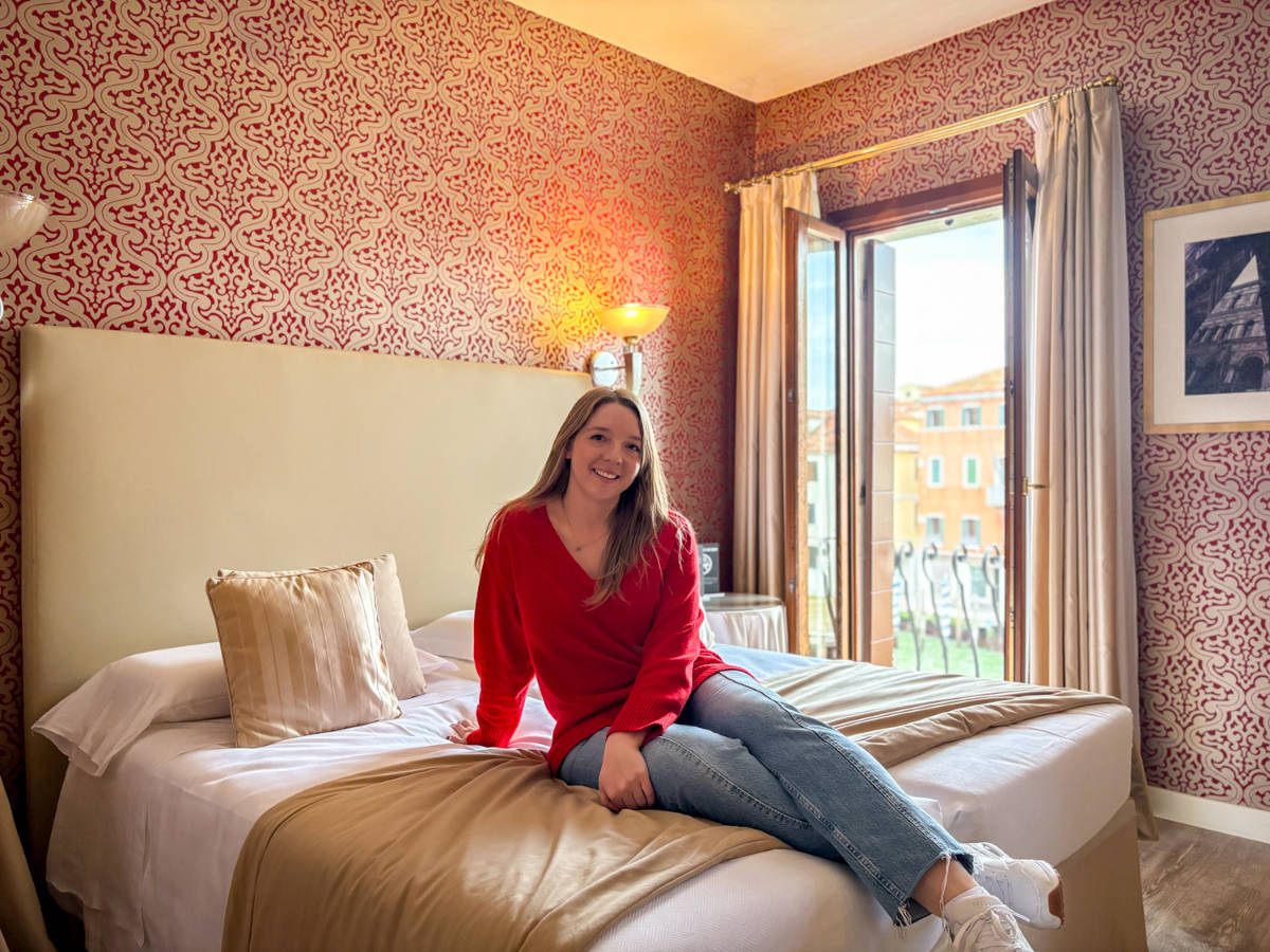 The author, Taylor Herperger sitting on her bed at Hotel Principe