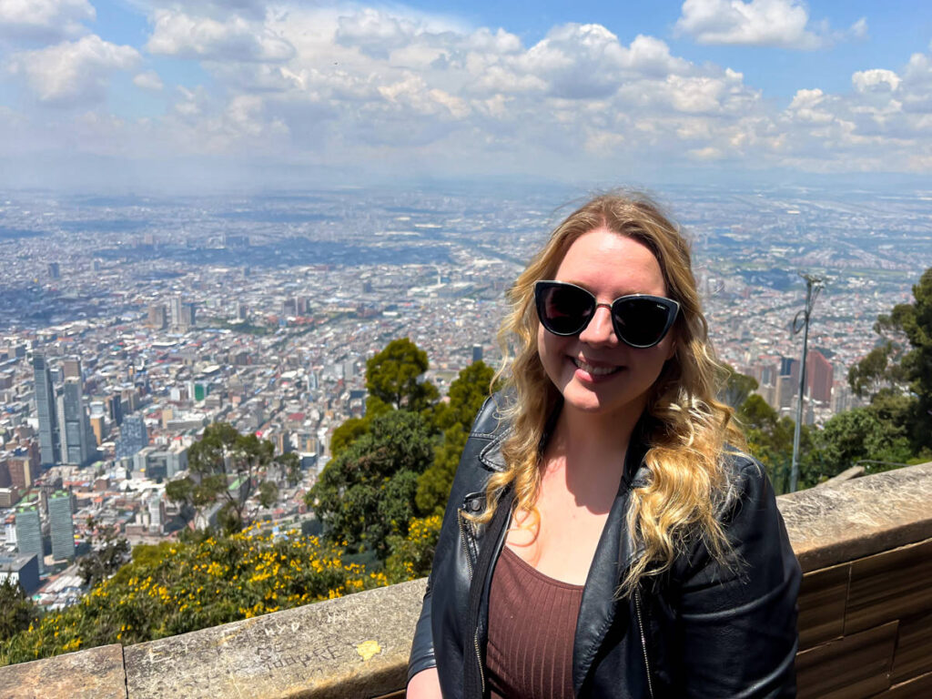 The author Taylor Herperger, smiling for a photo with an overlooking view of Bogota