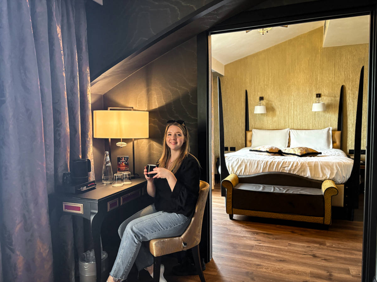 The author Taylor Herperger, sitting while holding a drinking in her suite at Palazzo Veneziano