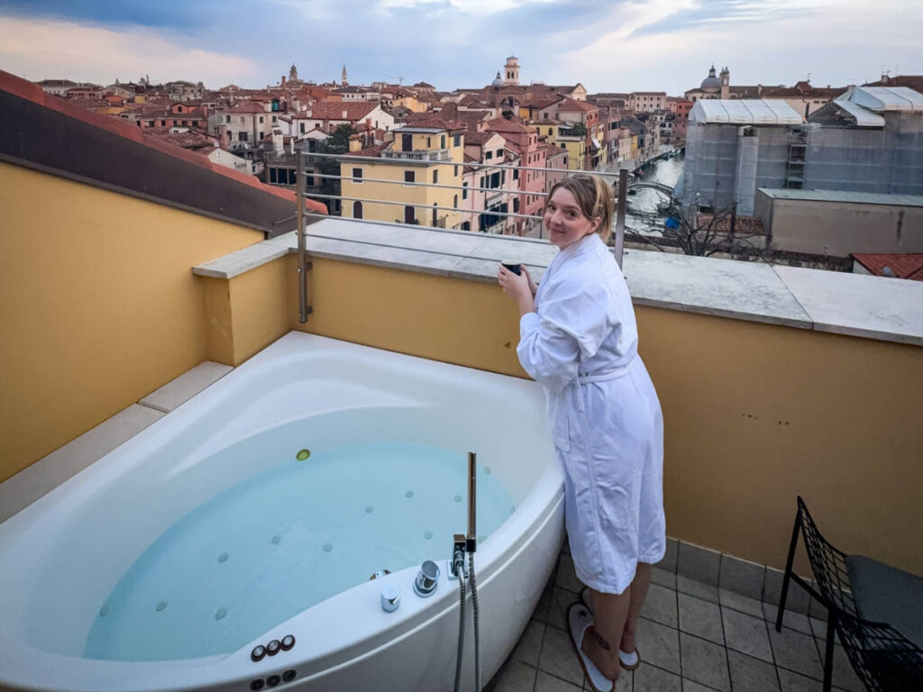 The author Taylor Herperger, standing next to the balcony jacuzzi at Palazzo Veneziano