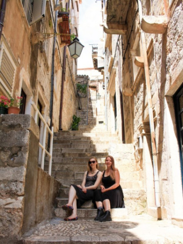Author Taylor Herperger and her friend sitting on the stairs in Dubrovnik
