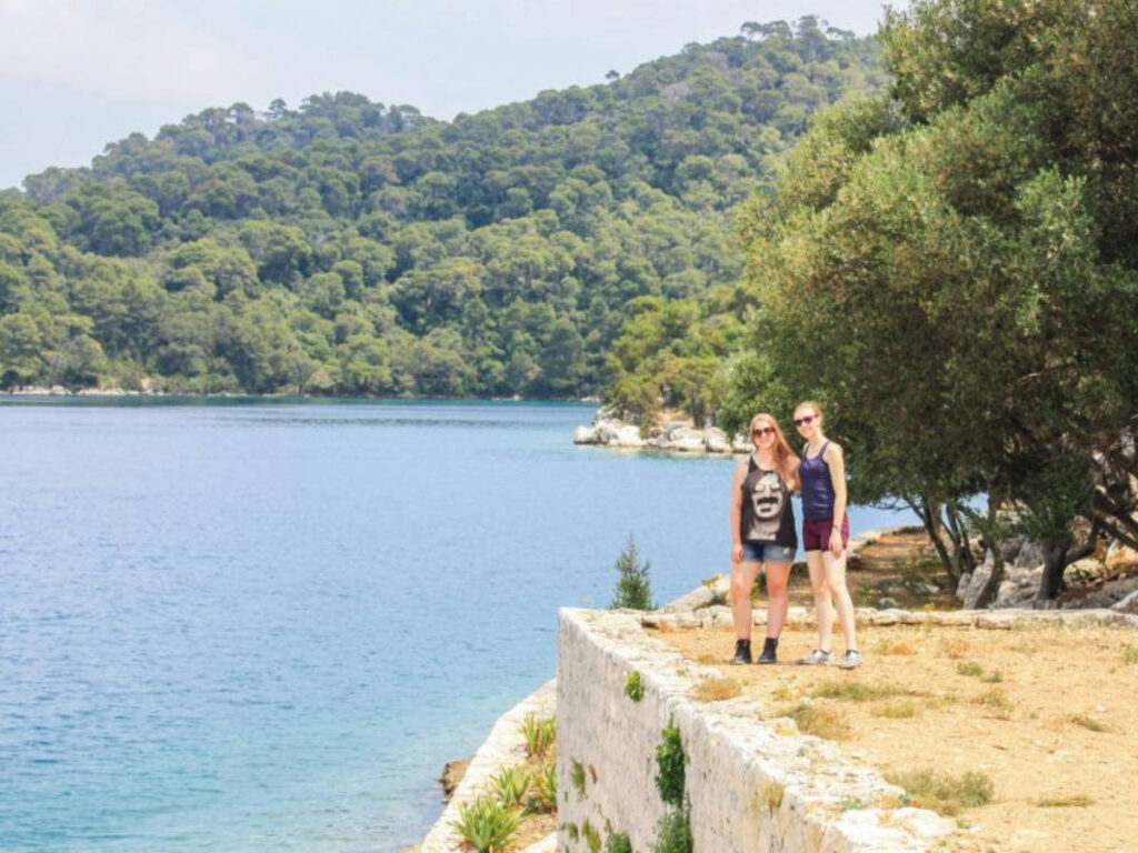 Taylor Herperger with her friend smiling for a photo at the cliffside of Mljet National Park
