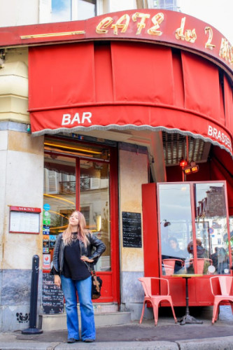 Travel Lemming's Senior Editor Taylor posing for a photo outside Café des Deux Moulins in Paris