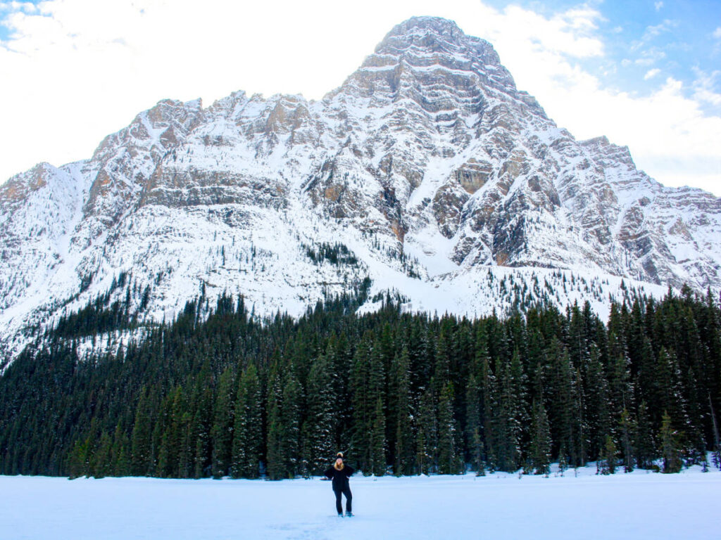 The author Taylor Herperger on the frozen Chephren Lake with scenic views of the mountain in the background