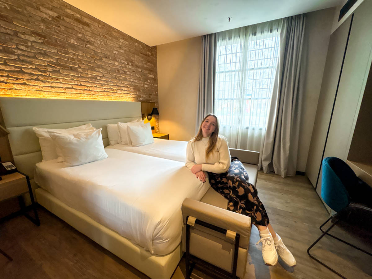 The author Taylor Herperger, sitting on her bed at Hotel NH Collection Venezia Murano Villa