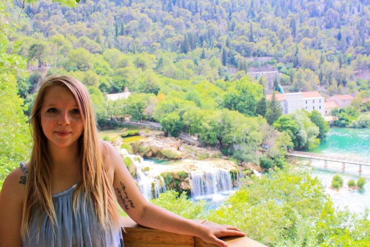 Taylor stands in front of waterfalls, turquoise lakes and green foliage at Krka National Park in June