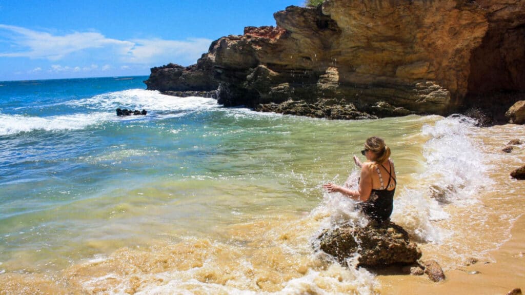The author Taylor Herperger, sitting on a rock while being hit by the waves in Puerto Rico