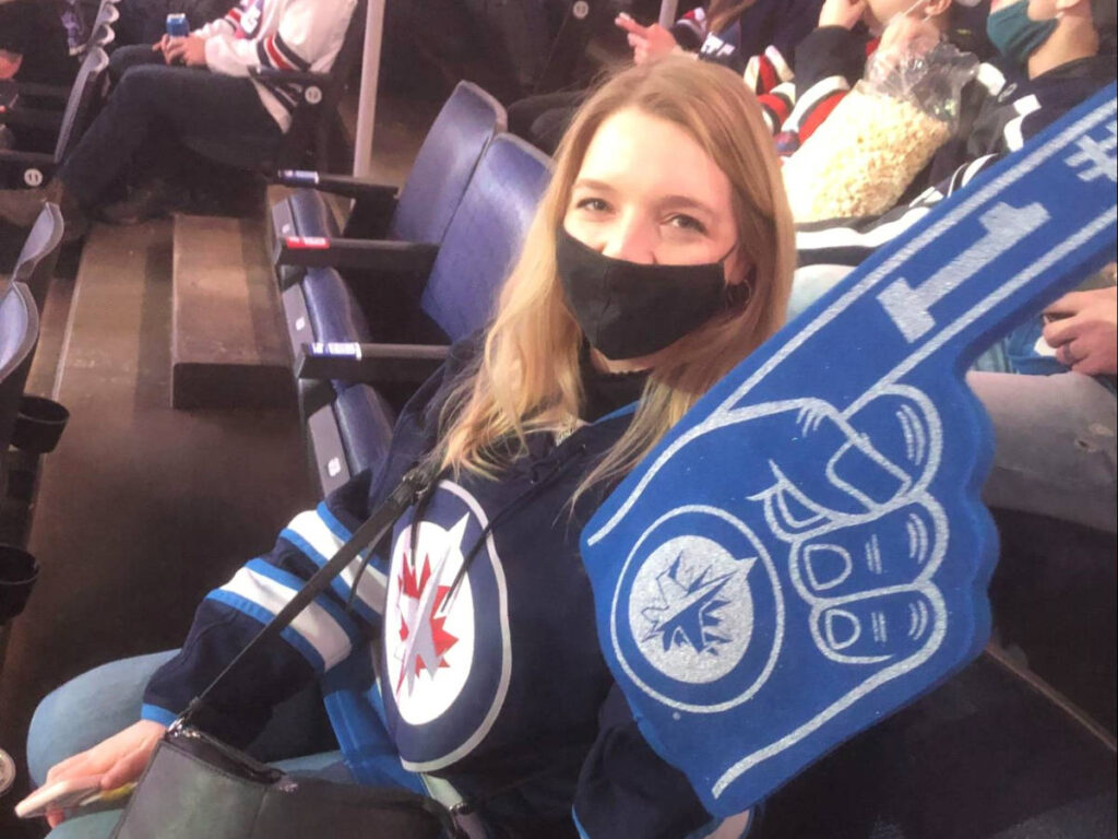 The author Taylor Herperger posing with a hand sign at a Winnipeg Jets game