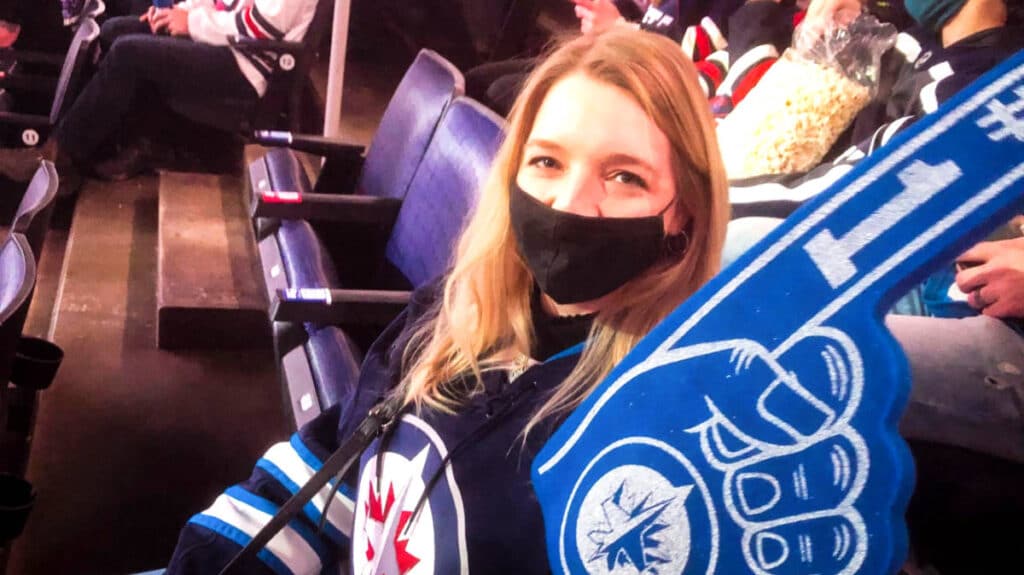 The author Taylor Herperger posing with a hand sign at a Winnipeg Jets game